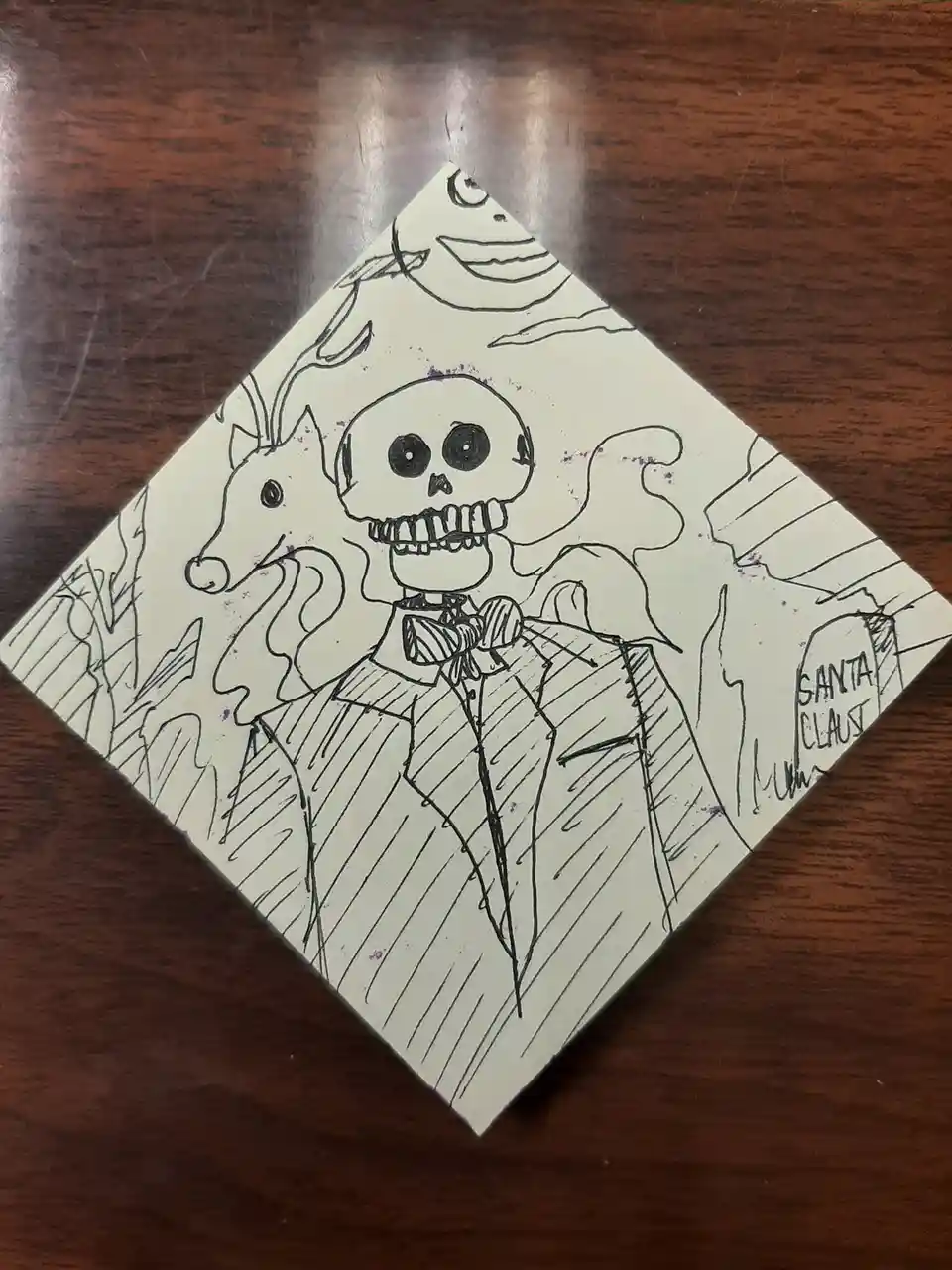 A hand-drawn, black-and-white sketch on a diamond-shaped piece of paper shows a skeletal figure in a suit and bowtie…
