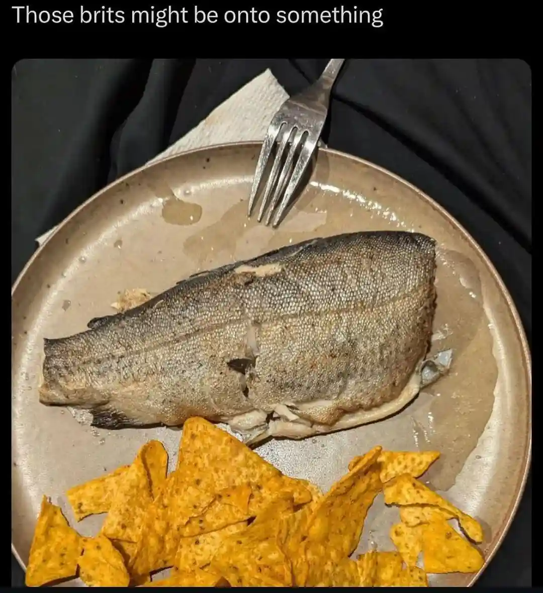 A close-up photo shows a cooked fish, likely a whole trout or similar, resting on a beige plate. A metal fork is stuck into…