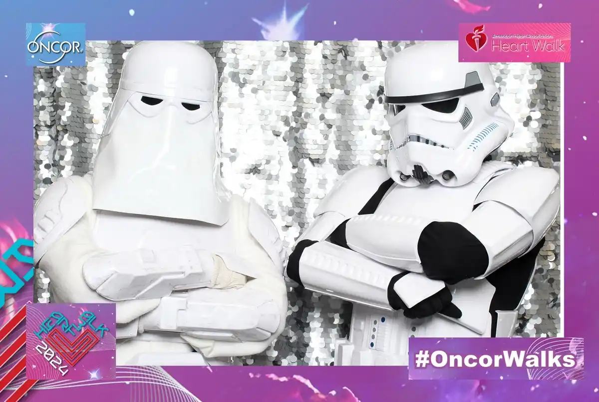 Two costumed characters, a stormtrooper and a snowtrooper from star wars, stand side by side with arms crossed in front of a…