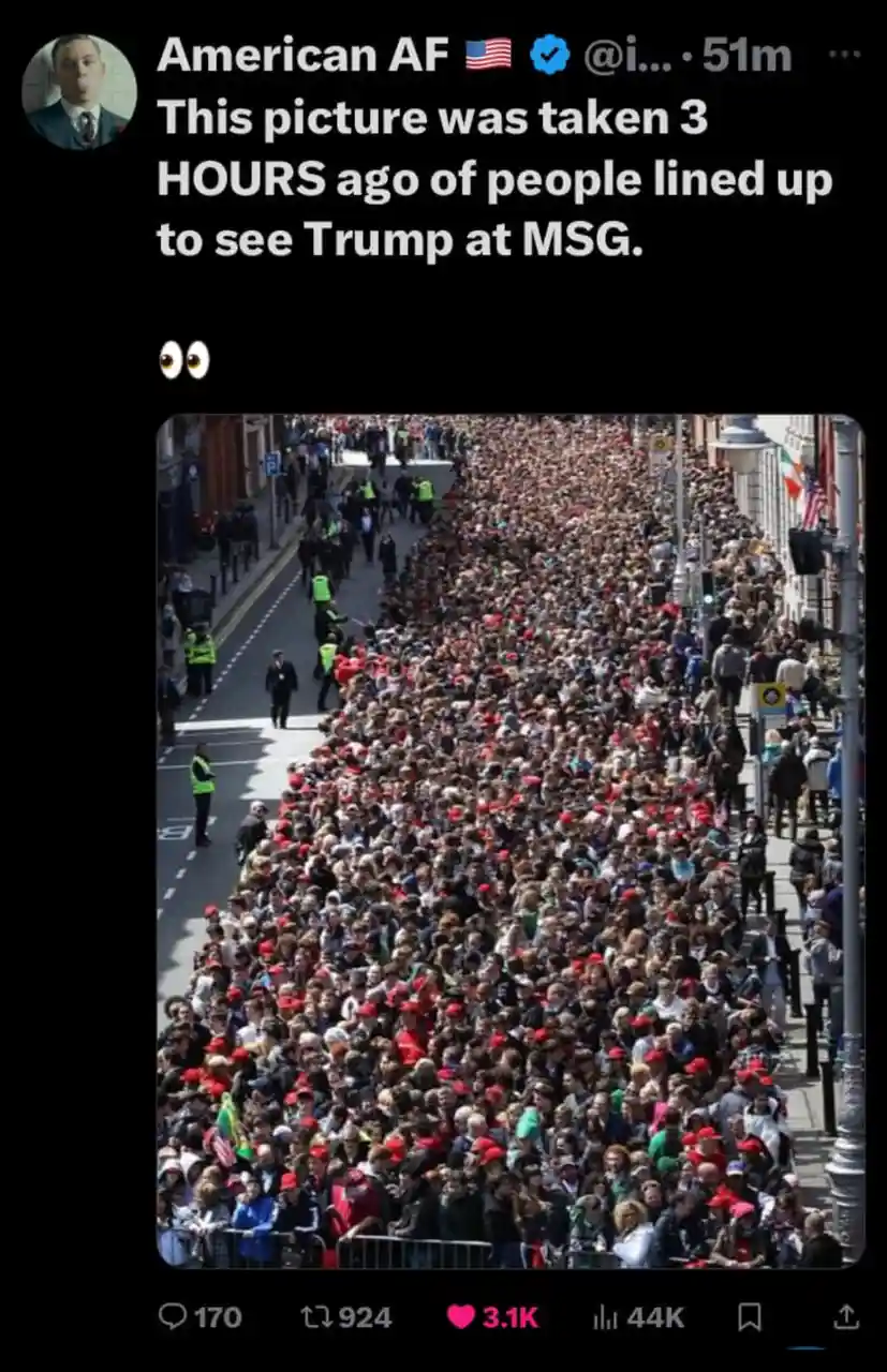 A high-angle photo shows a massive, dense crowd of people filling a city street, many wearing red hats, with police officers…