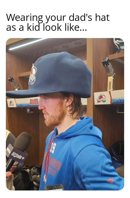 A man with a beard and wet hair wears a large, oversized blue baseball cap backwards while being interviewed in a locker…