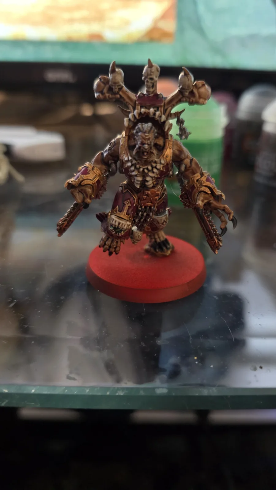 A heavily detailed, hand-painted fantasy miniature of a monstrous, skeletal humanoid warrior stands on a red circular base…
