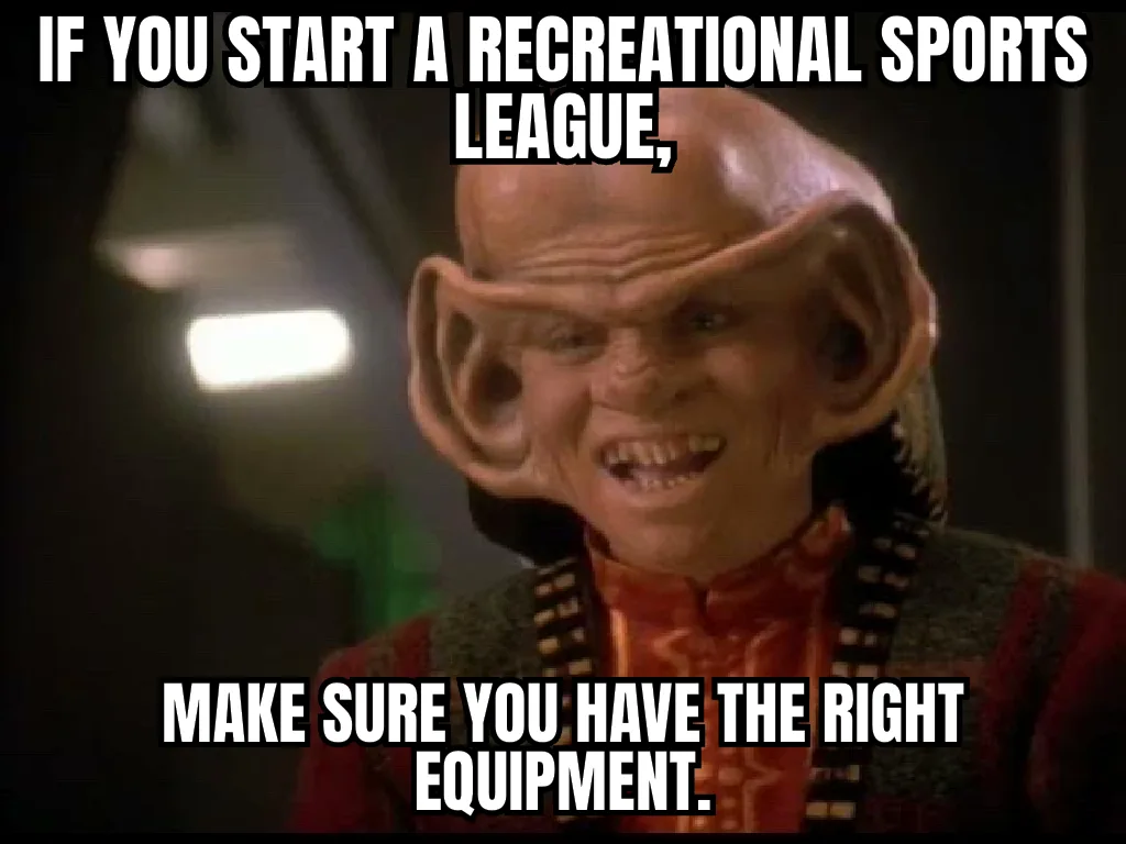 A close-up of a bald, alien character with large, pointed ears and a menacing grin, wearing a red and black patterned…