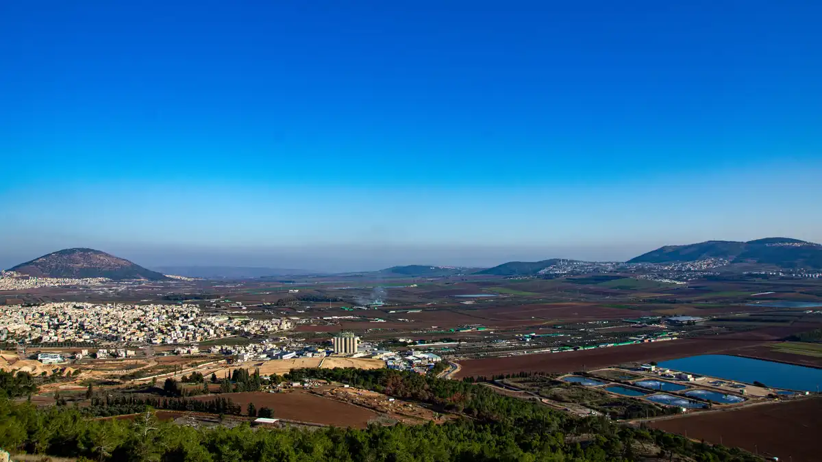 A wide landscape photo shows a valley with towns, farmland, and hills under a clear blue sky. Overlaid text reads 'i'm not…