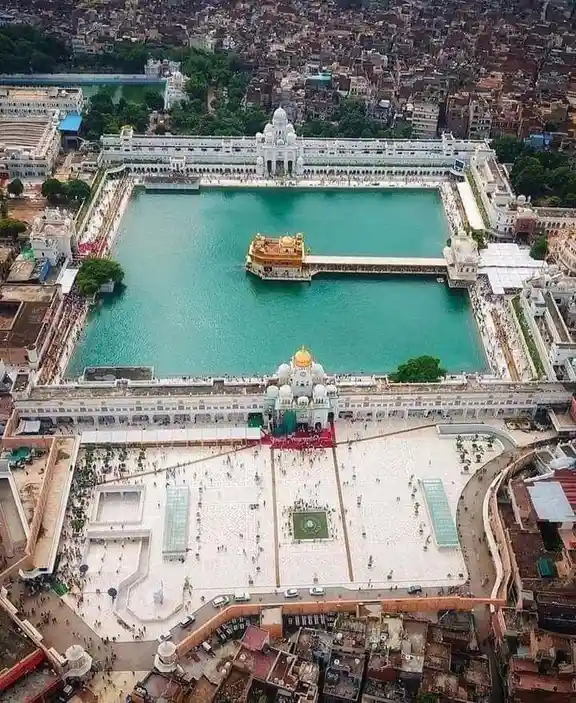 An aerial view of the Golden Temple in Amritsar, India, showing its iconic golden-domed shrine surrounded by a large…