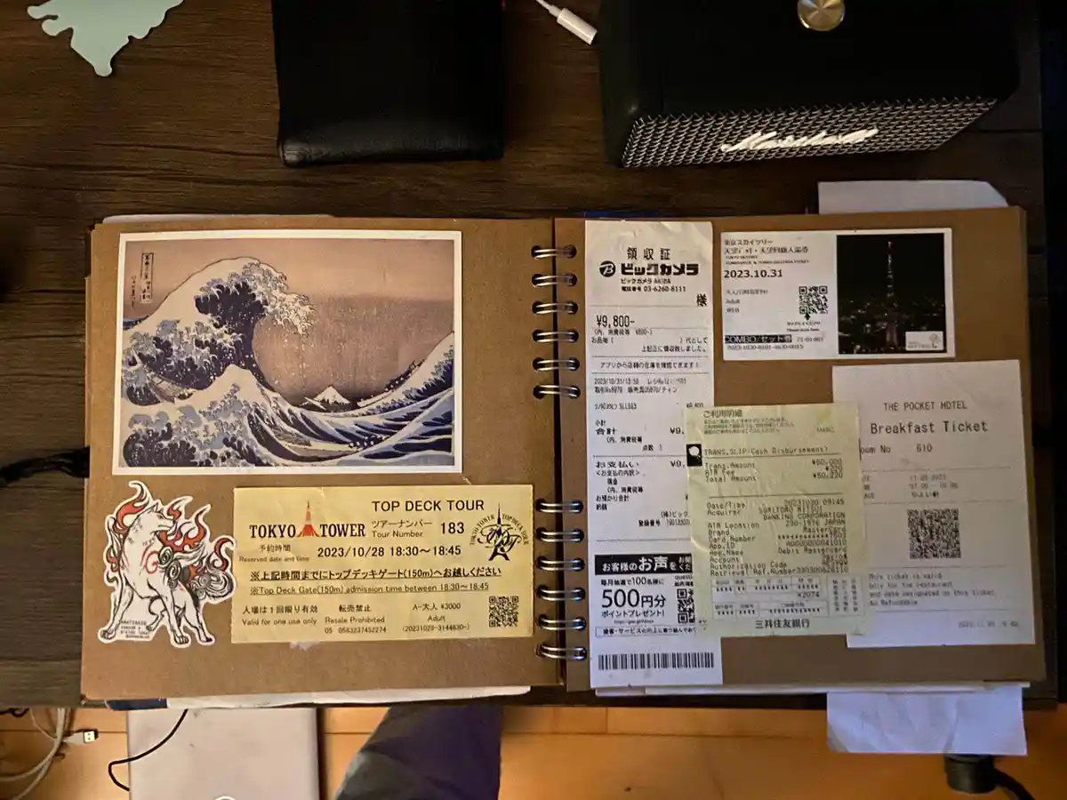 a spiral-bound travel journal displays various japanese receipts and tickets including a tokyo tower tour, a tokyo skytree…