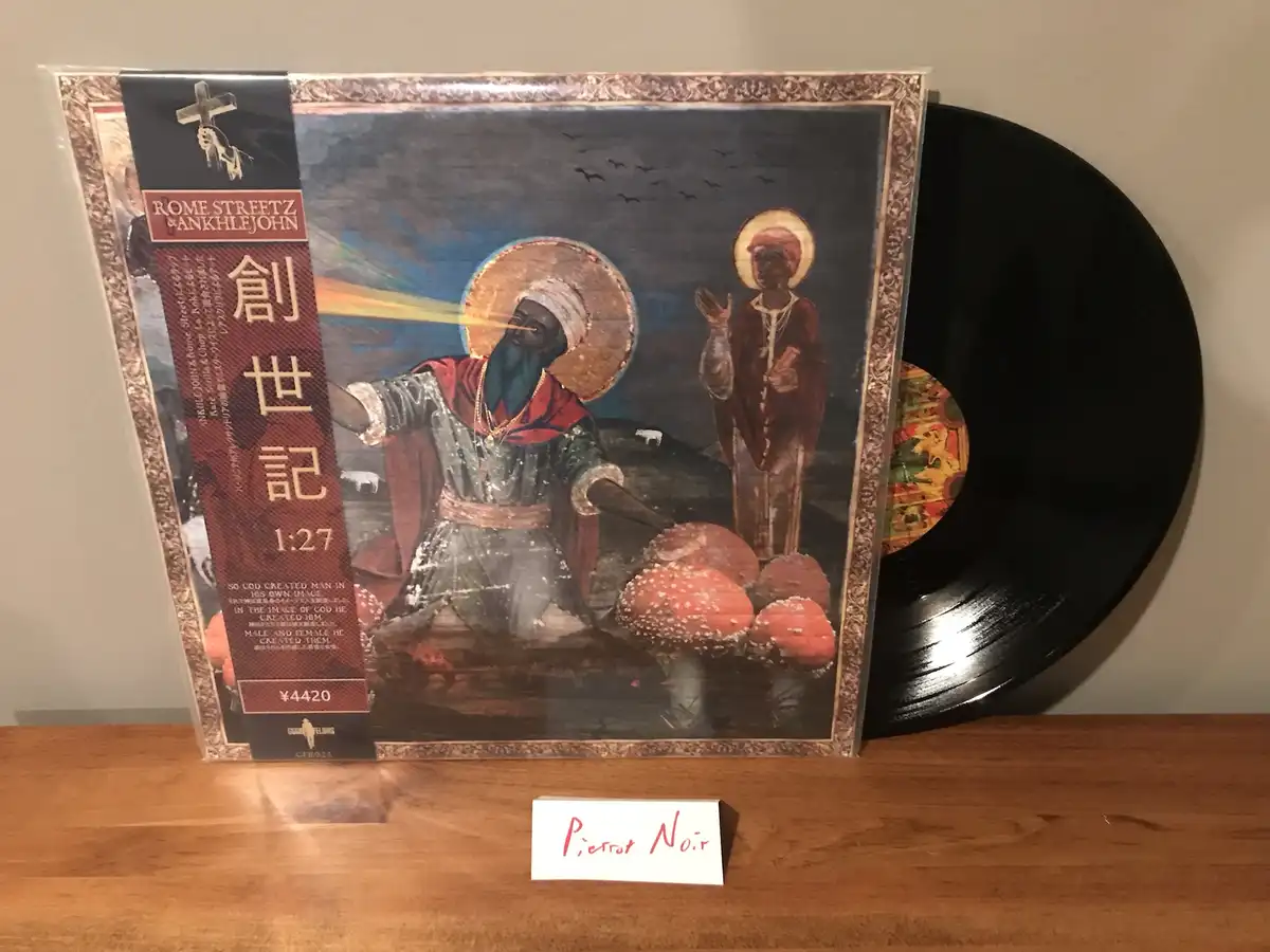 A vinyl record with an album cover depicting two Black figures in religious-style iconography, one emitting a beam of light…