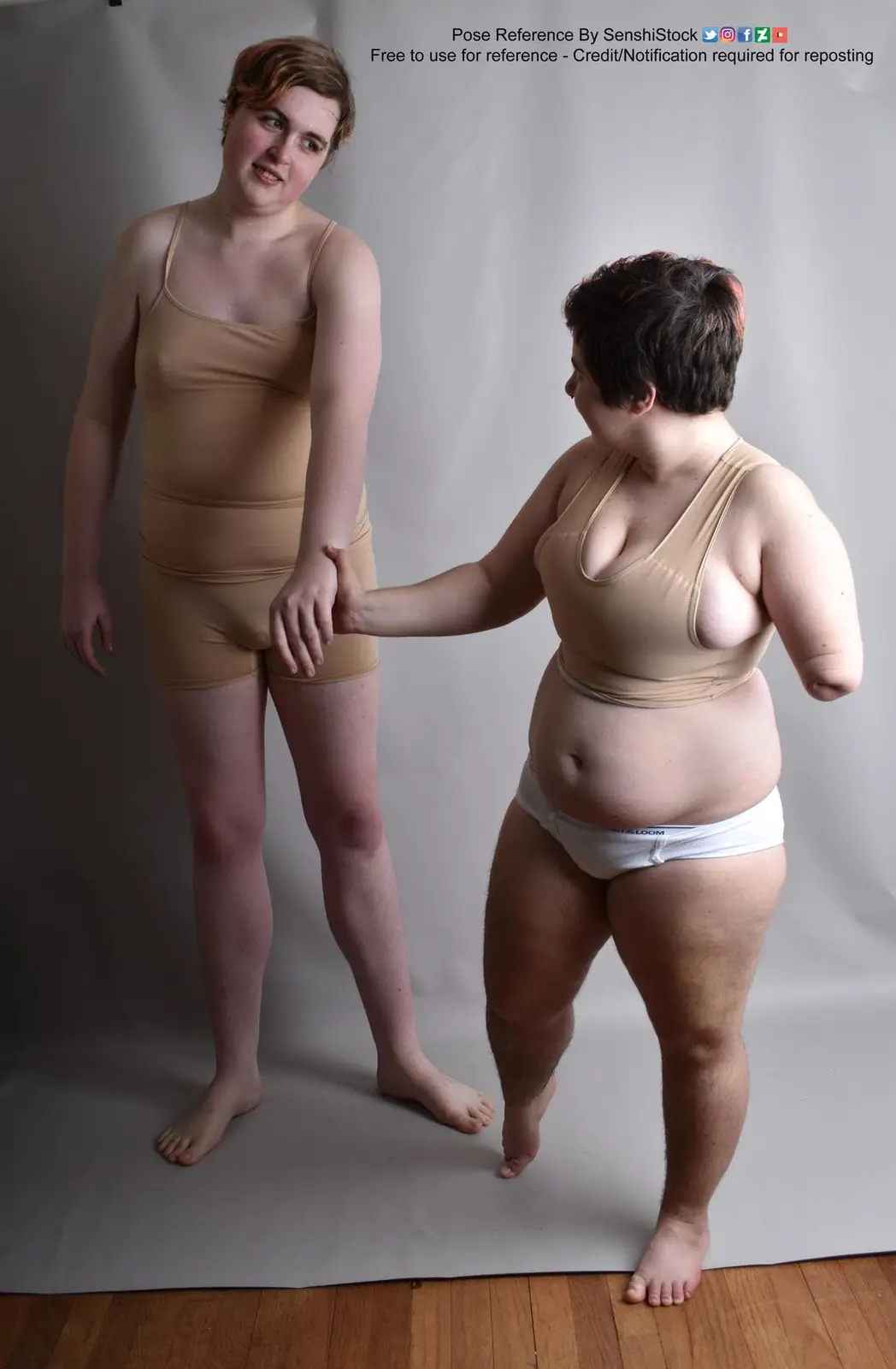 Two people stand against a plain backdrop; one is slender in a tan bodysuit, the other is plus-sized in a tan top and white…