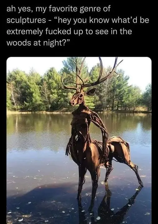 A metal sculpture of a deer with antlers stands in shallow water, its body constructed from twisted, rusted metal pieces…