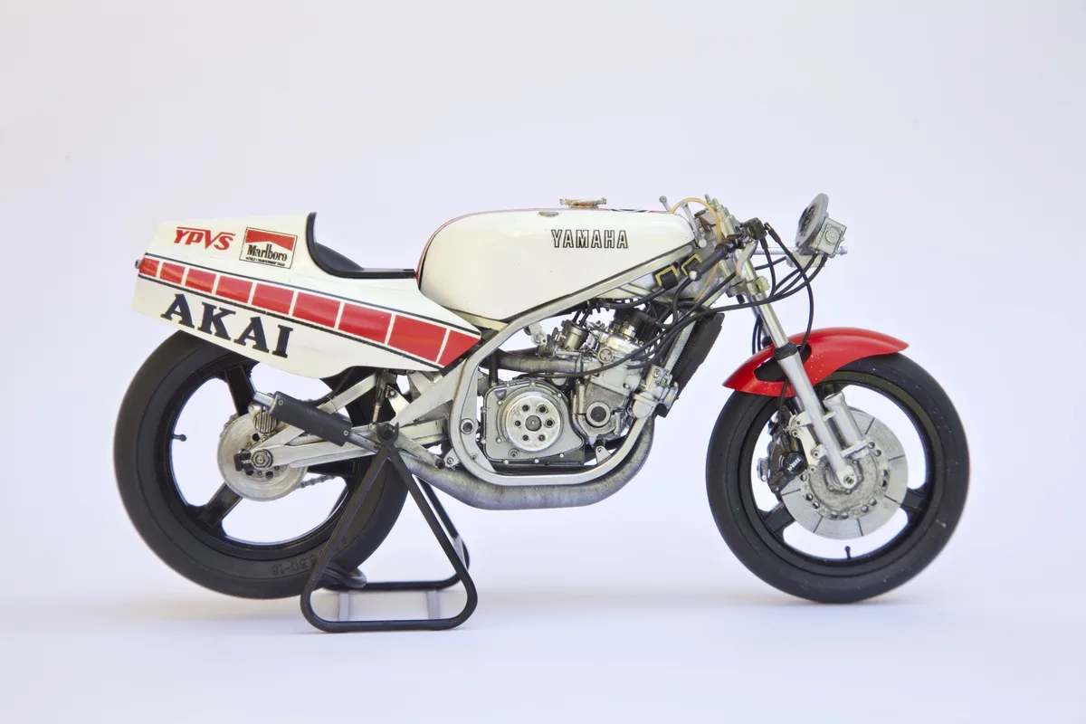 A detailed scale model of a white and red Yamaha racing motorcycle with 'AKAI' written in large black letters on the side…