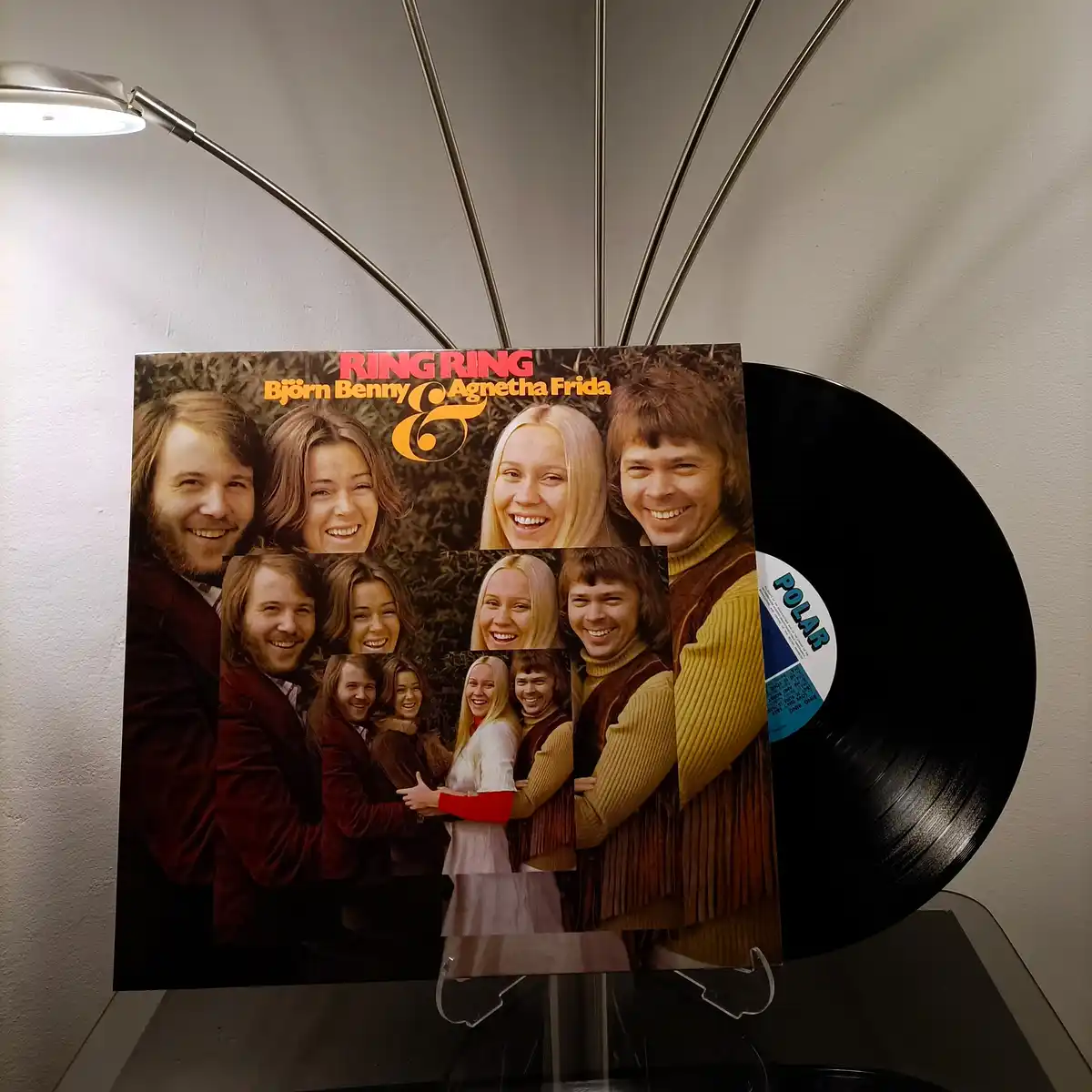 A vinyl record of ABBA's 'Ring Ring' album is displayed, with its cover art featuring the band members smiling. The cover…