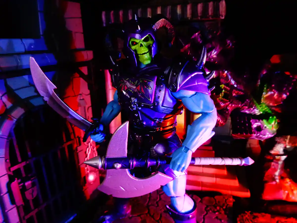 A green-skulled, horned action figure resembling Skeletor from Masters of the Universe stands in a dimly lit, dungeon-like…