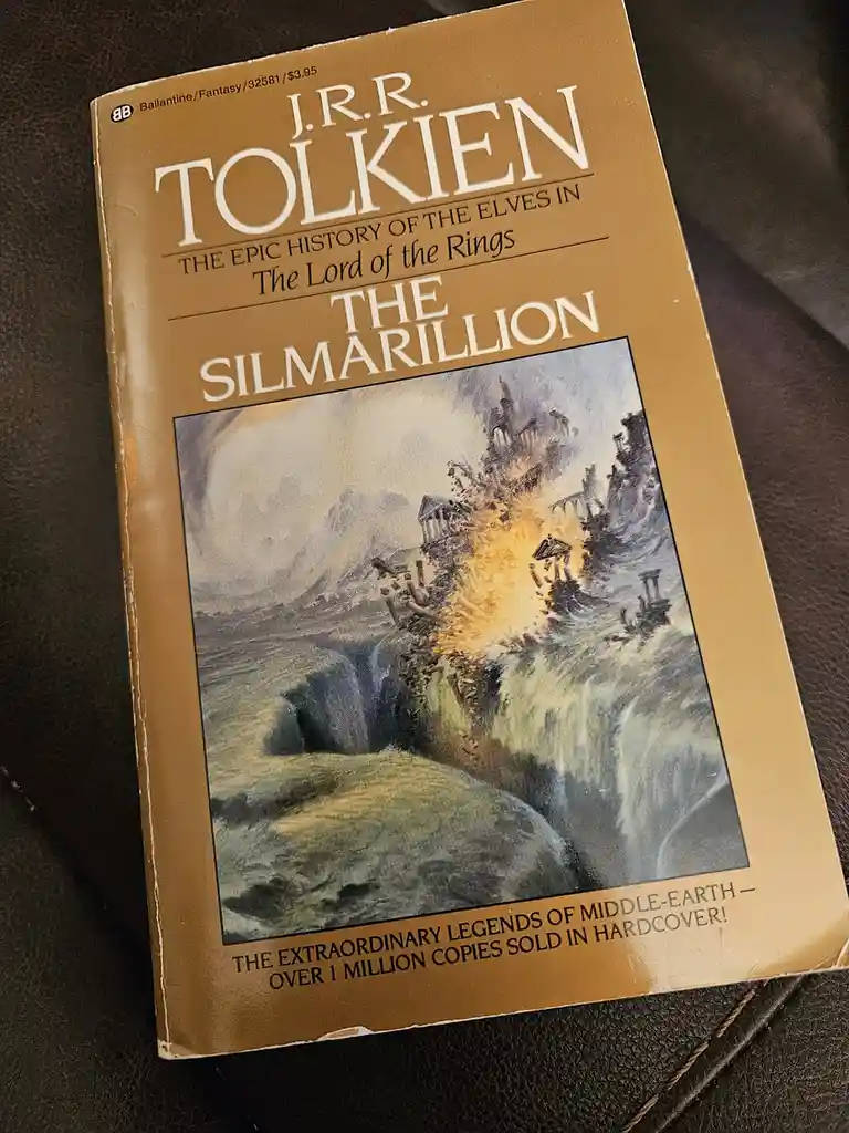A vintage hardcover book titled 'The Silmarillion' by J.R.R. Tolkien, with a cover illustration depicting a fiery explosion…