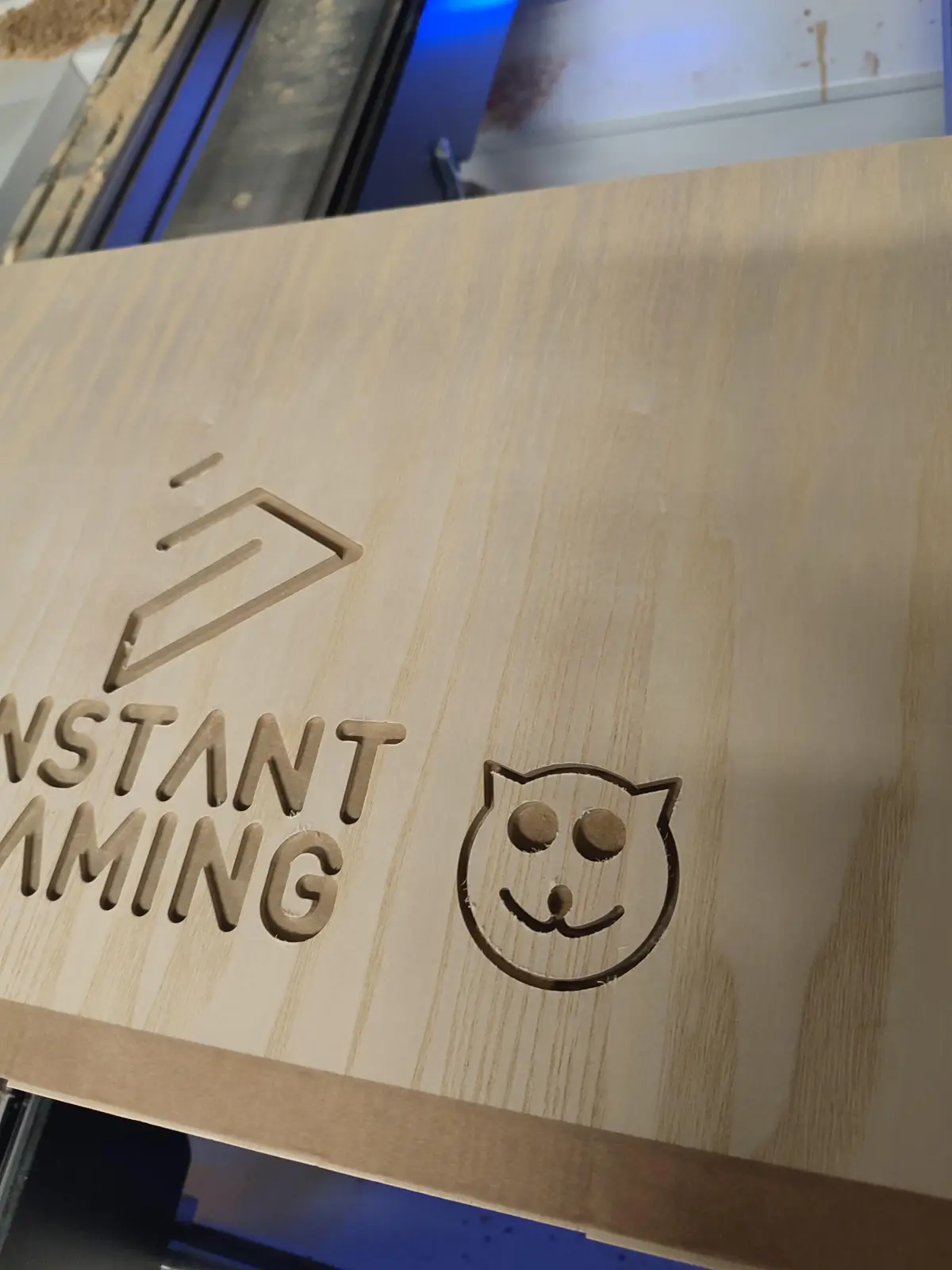 A close-up of a light-colored wooden board with laser-cut text and logos. The text reads 'INSTANT GAMING' in bold, uppercase…