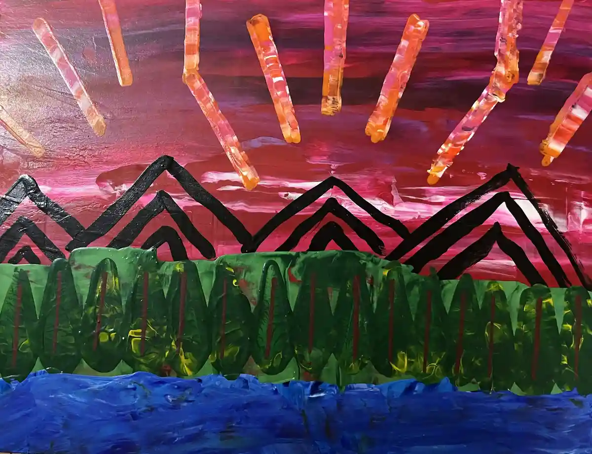 A child's painting depicts a vibrant sunset scene with a pink and red sky, orange sun rays, black jagged mountains, green…