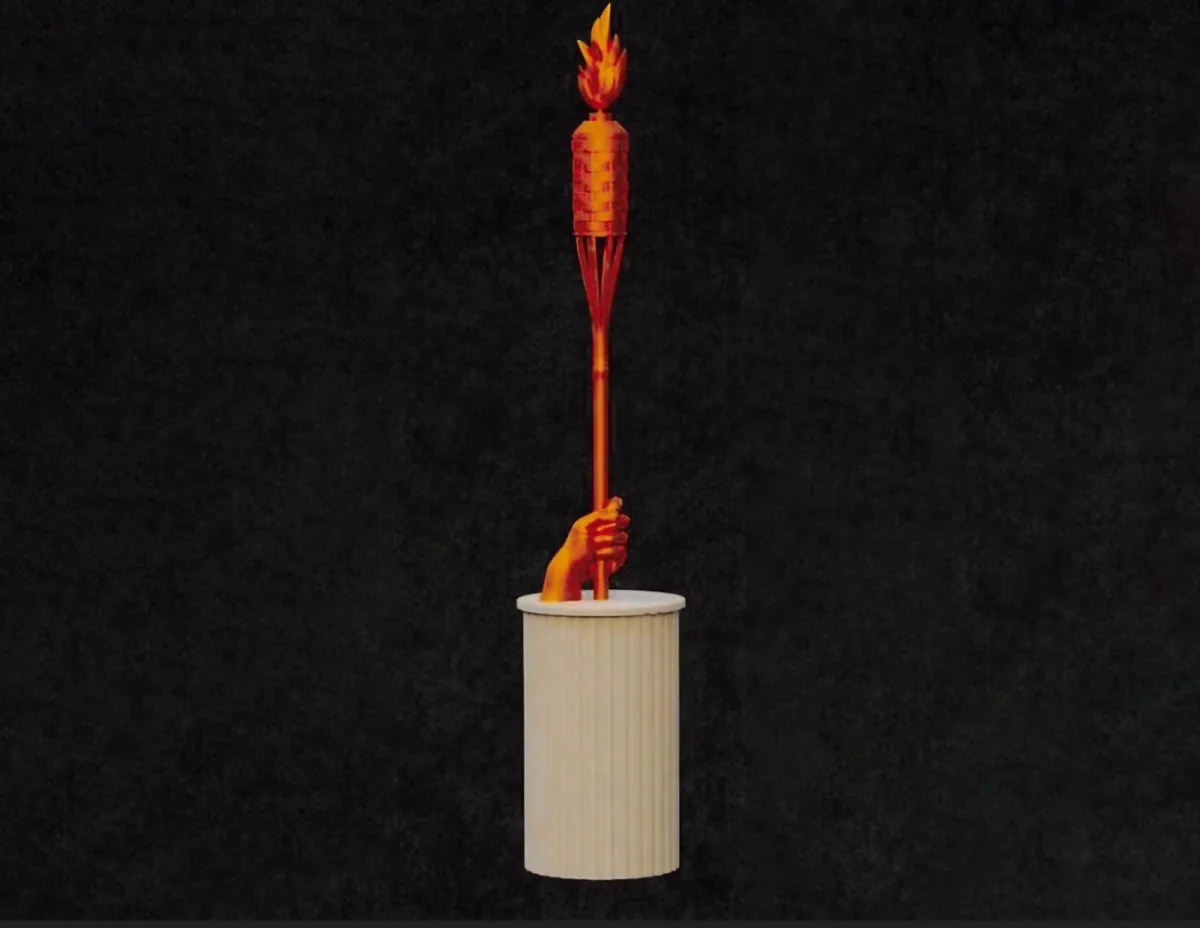 A statue of a hand holding an Olympic torch with a flame on top, mounted on a white pedestal against a dark background. The…