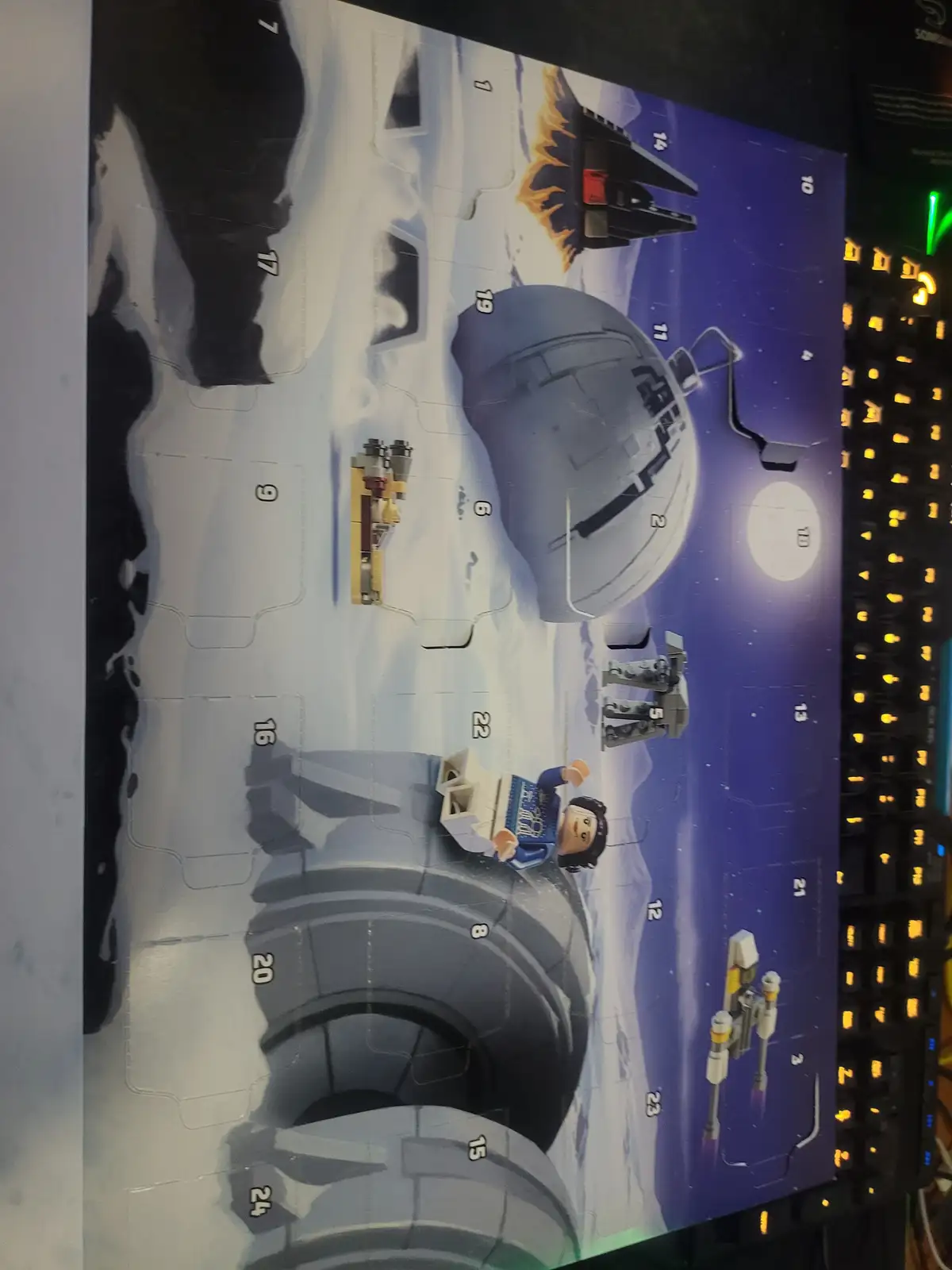 A close-up photo of a LEGO Star Wars Advent Calendar, showing its illustrated front with numbered compartments depicting…