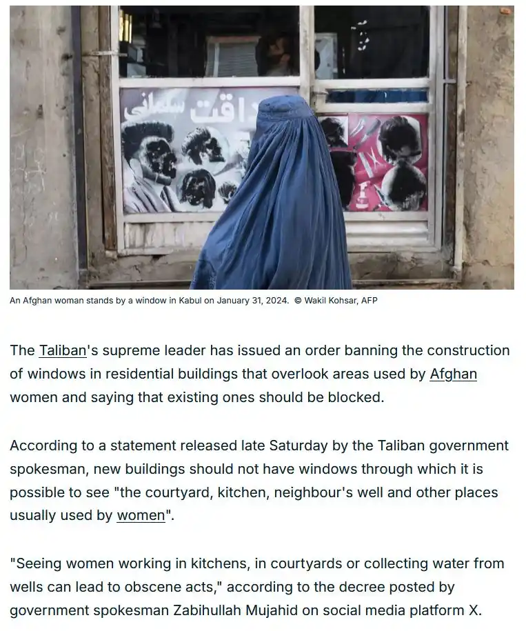A woman in a blue burqa stands with her back to the camera, looking out a window in a weathered building in Kabul. Behind…