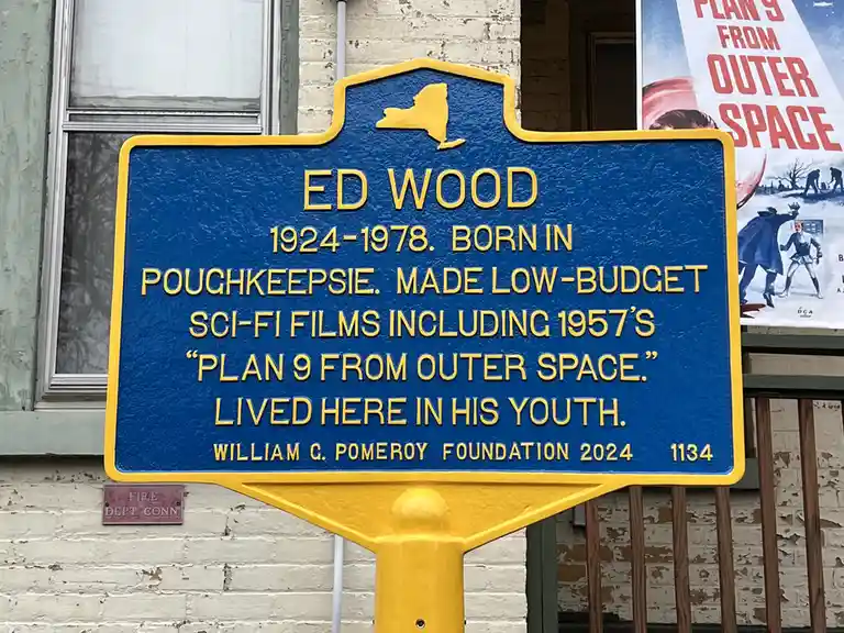A blue and yellow New York state historical marker commemorates Ed Wood, noting his birthplace, low-budget sci-fi films like…