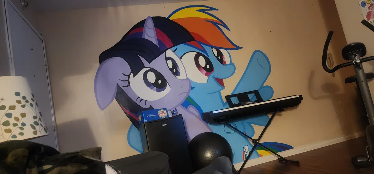 A wall mural of two My Little Pony characters, Twilight Sparkle and Rainbow Dash, with a keyboard placed on a stand over…