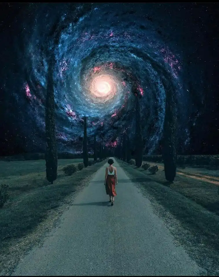 A person walks down a rural road lined with tall, dark trees, heading toward a surreal, spiraling galaxy that forms the sky…