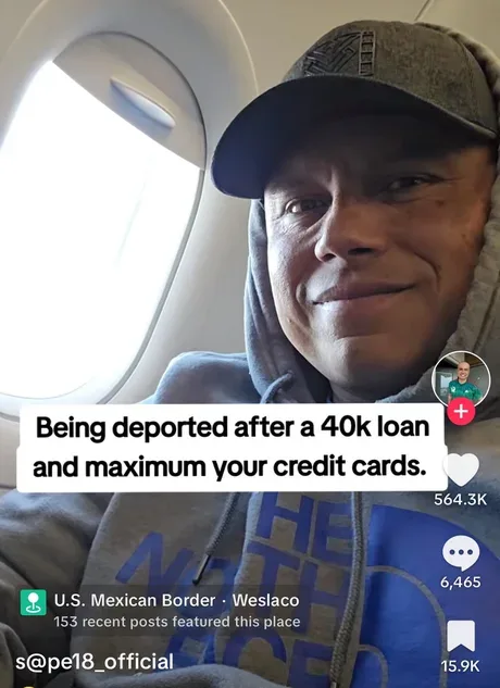 A man wearing a grey hoodie and cap sits inside an airplane cabin, smiling slightly while looking at the camera. An airplane…