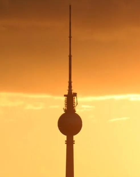 A silhouette of the Berlin TV Tower against a warm orange sunset sky. The image is overlaid with the text 'i'm not a fan of…