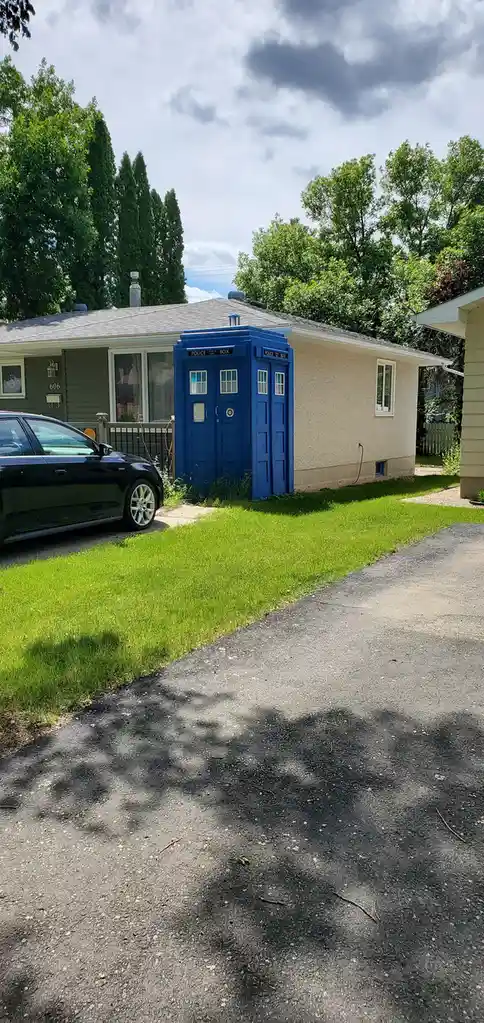 A blue police public call box, famously known as the TARDIS from Doctor Who, is visibly attached to the side of a beige…