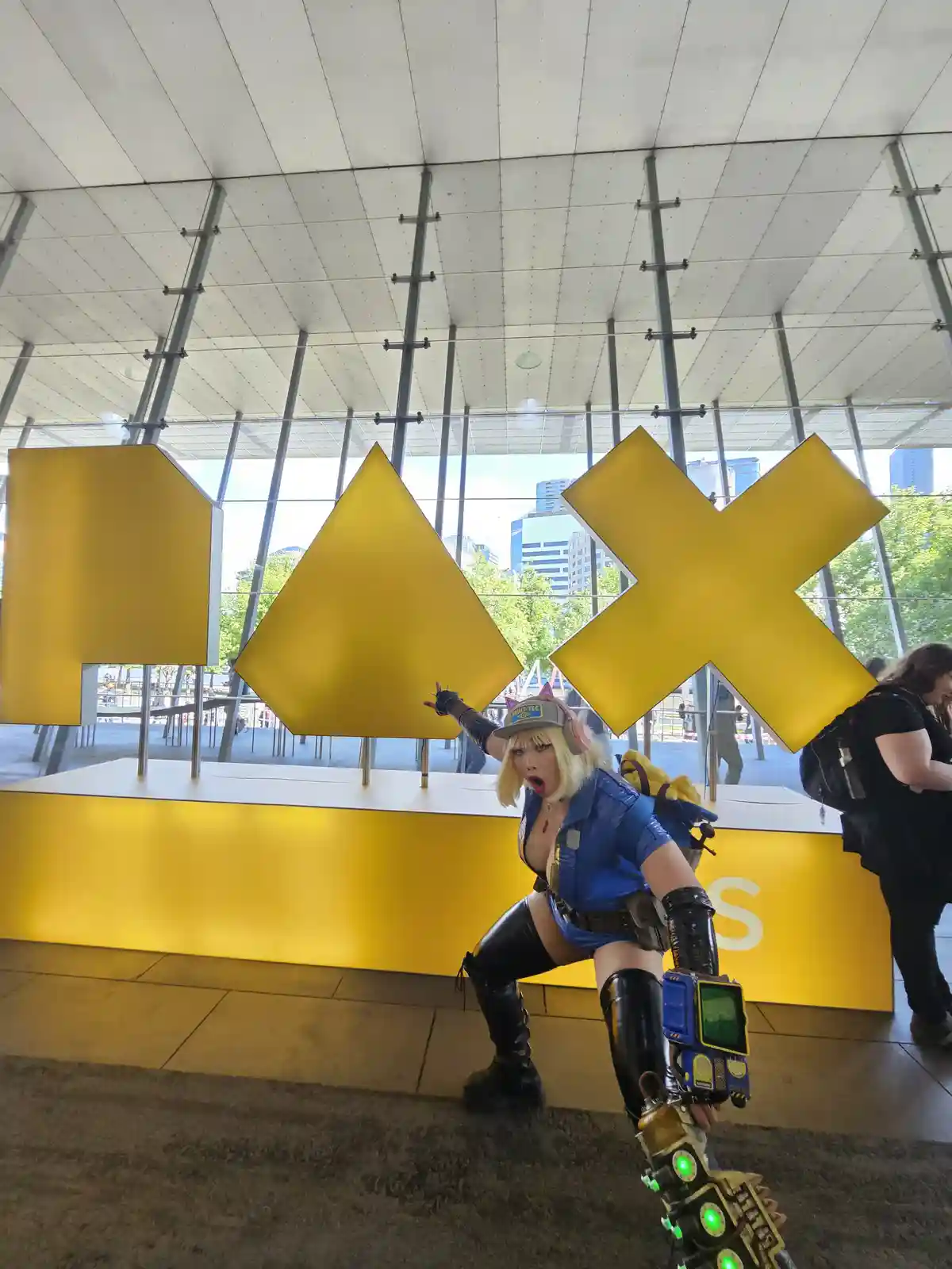A person in a detailed cosplay of a video game character, likely from 'Borderlands', poses dramatically in front of large…