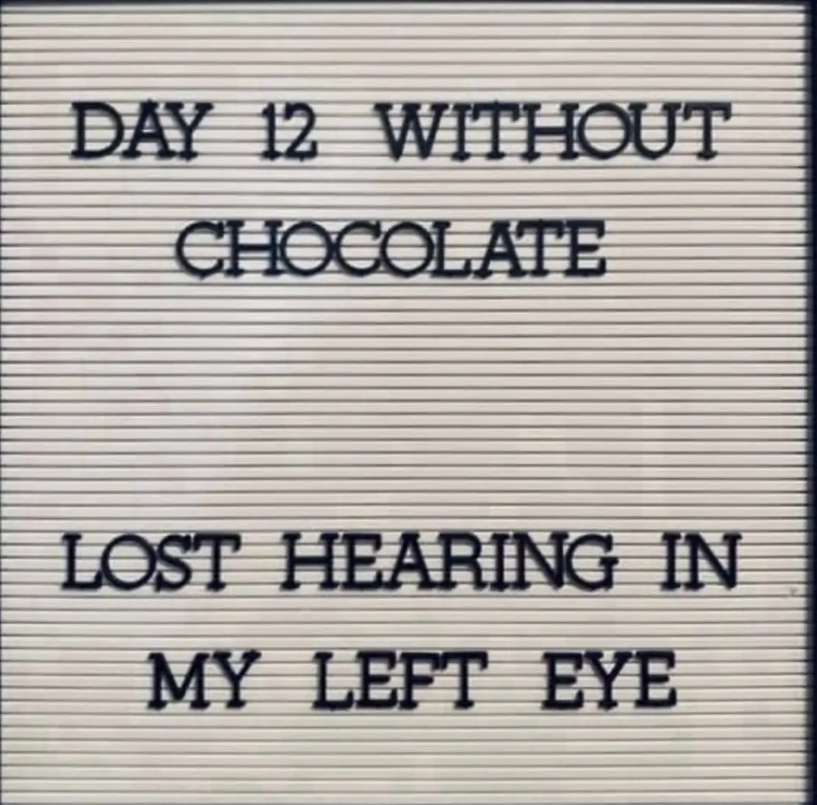 A light-colored letterboard with dark blue, uppercase letters displays the text 'DAY 12 WITHOUT CHOCOLATE' at the top and…