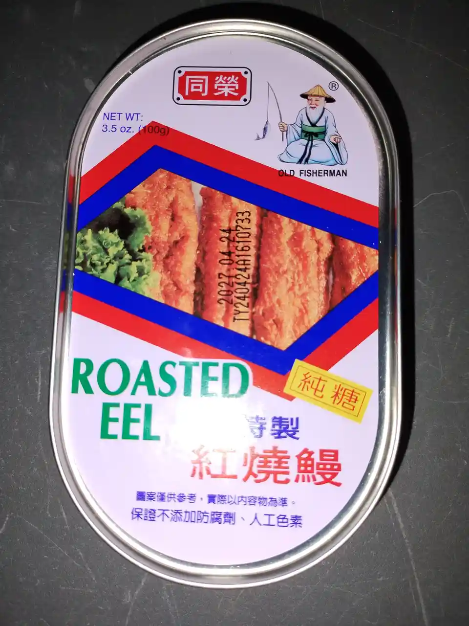 A close-up of a canned food label for 'ROASTED EEL' (紅燒鰻) by the brand 'OLD FISHERMAN', featuring an illustration of a…