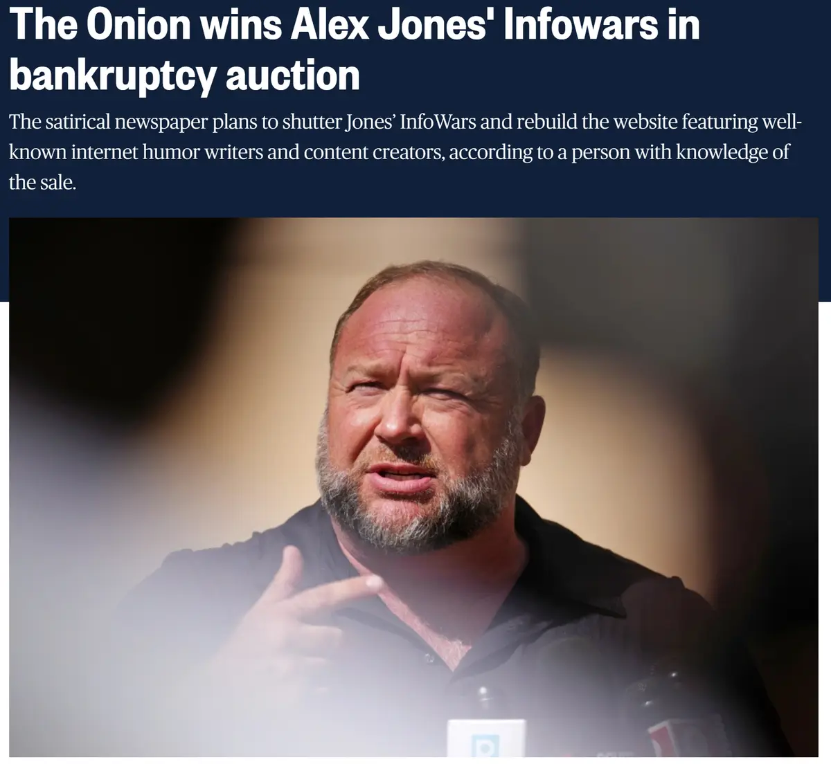 The image shows a close-up of Alex Jones speaking at a press event, with microphones visible in front of him. Overlaid text…
