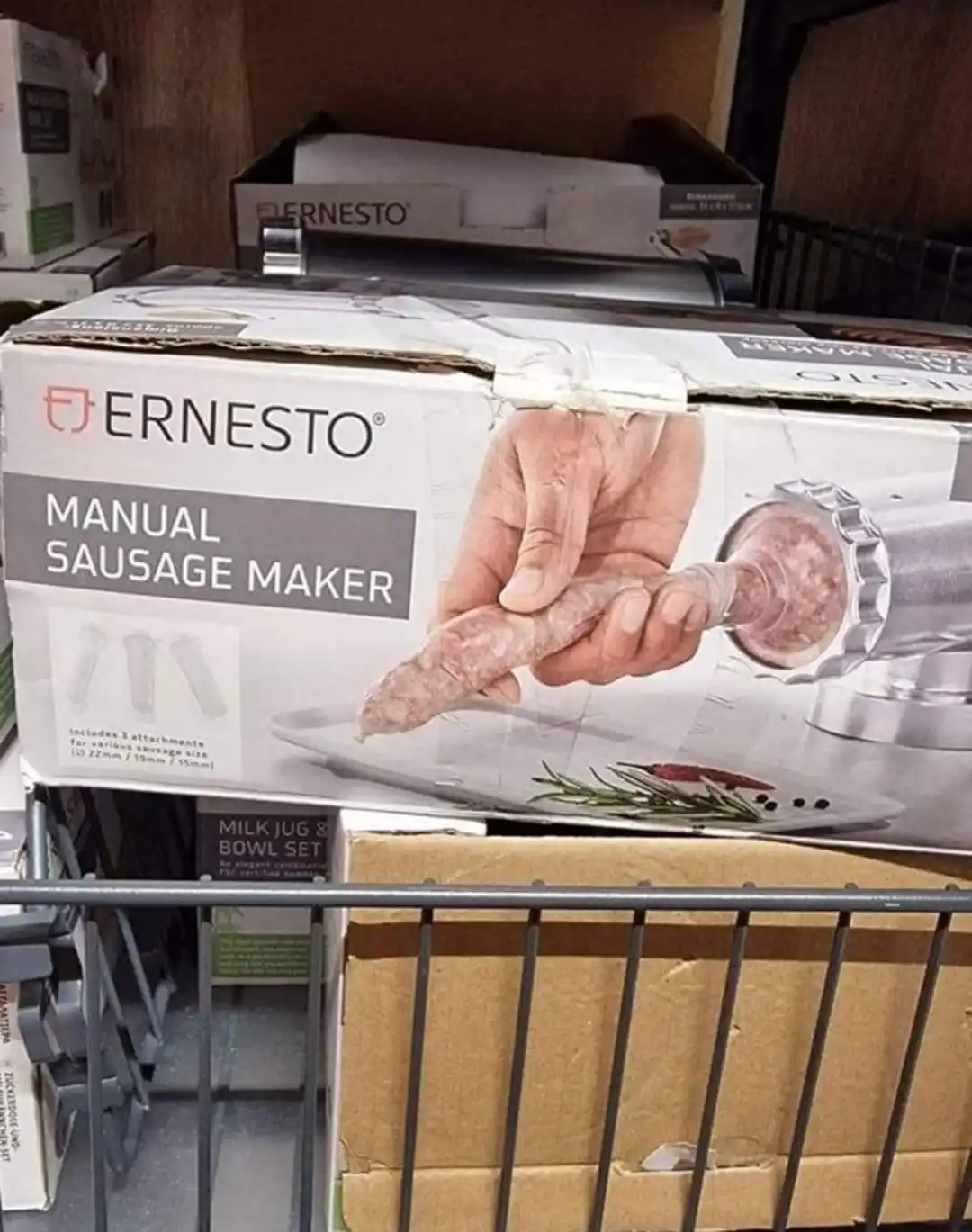 A product box for an Ernesto manual sausage maker sits on a store shelf, showing a hand holding a freshly made sausage…