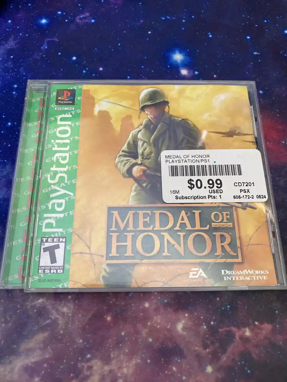 A physical PlayStation 1 game case for 'Medal of Honor' is shown, featuring artwork of a soldier in combat gear. A white…