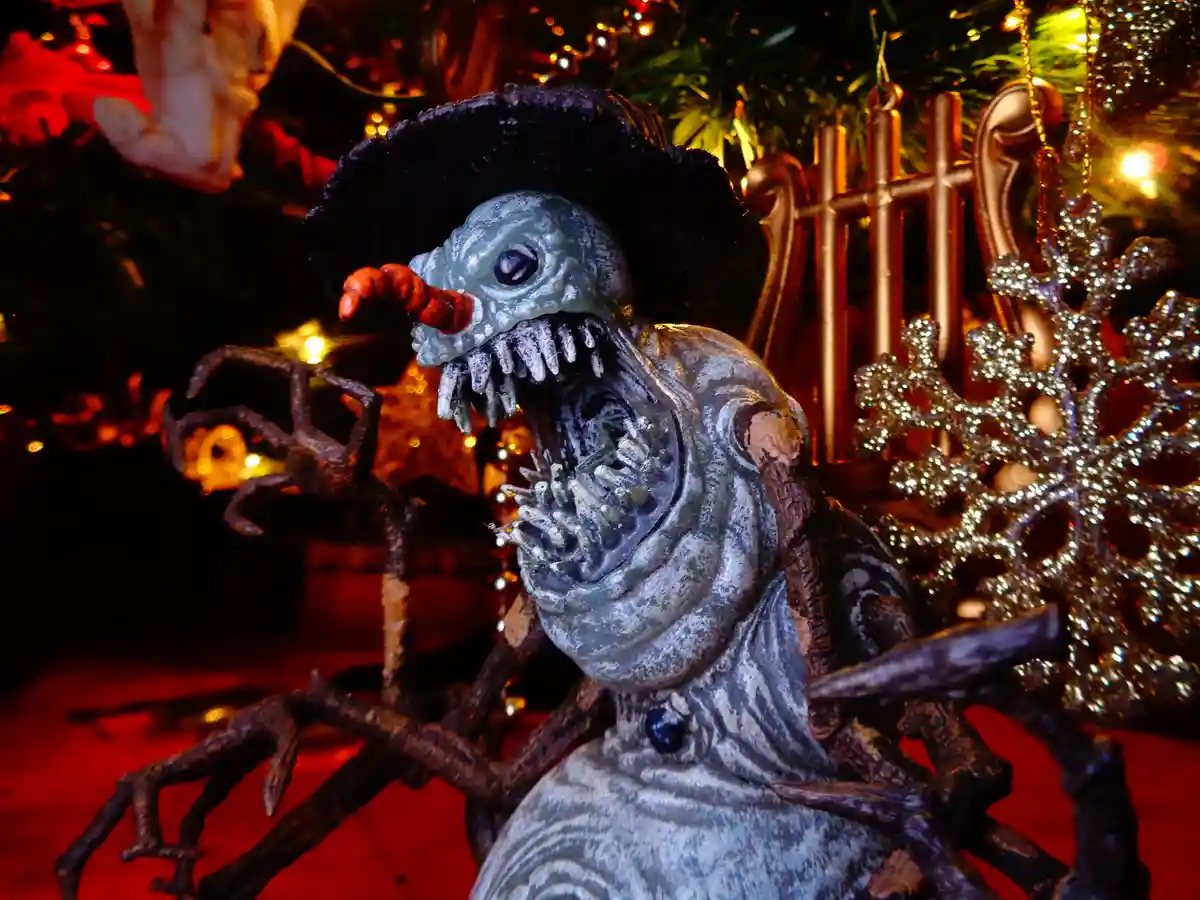 A grotesque, monstrous snowman figurine with a wide, toothy grin, a carrot nose, and twig-like limbs, sits in front of a…