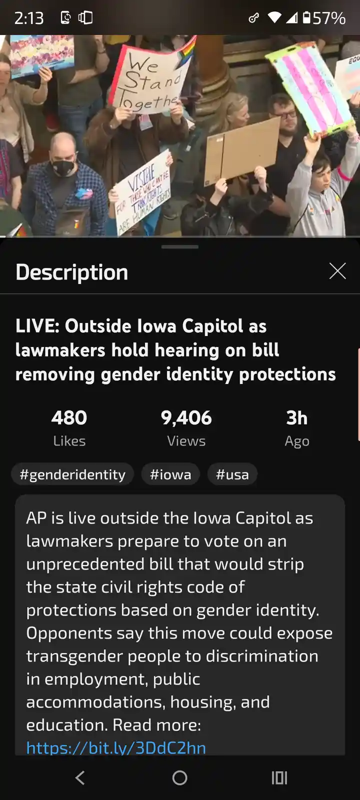 A crowd of protesters holds signs outside the Iowa Capitol building during a live news broadcast about a bill removing…