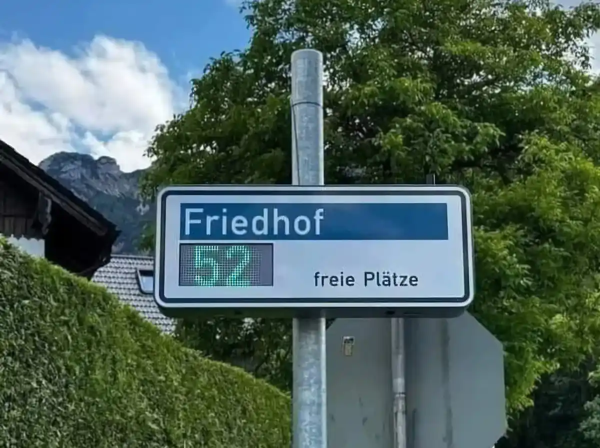 A digital sign at a German cemetery entrance displays 'Friedhof' and '0 freie Plätze' (0 free spaces), humorously implying…