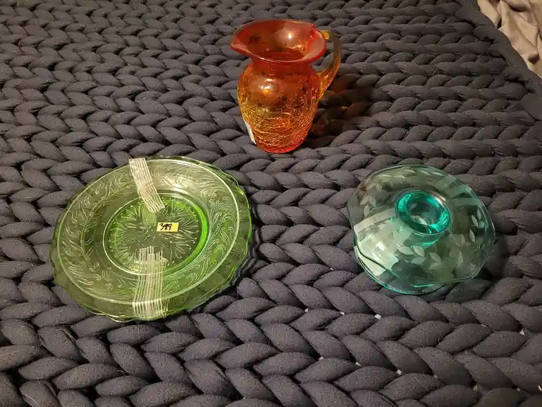 Three vintage glass items — a green patterned plate with a yellow '389' price tag, a red-orange crackled glass pitcher, and…