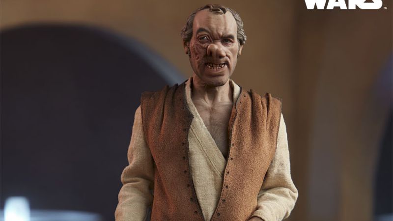 A close-up of a Star Wars action figure depicting a man with a grotesque, distorted, and angry facial expression, wearing a…