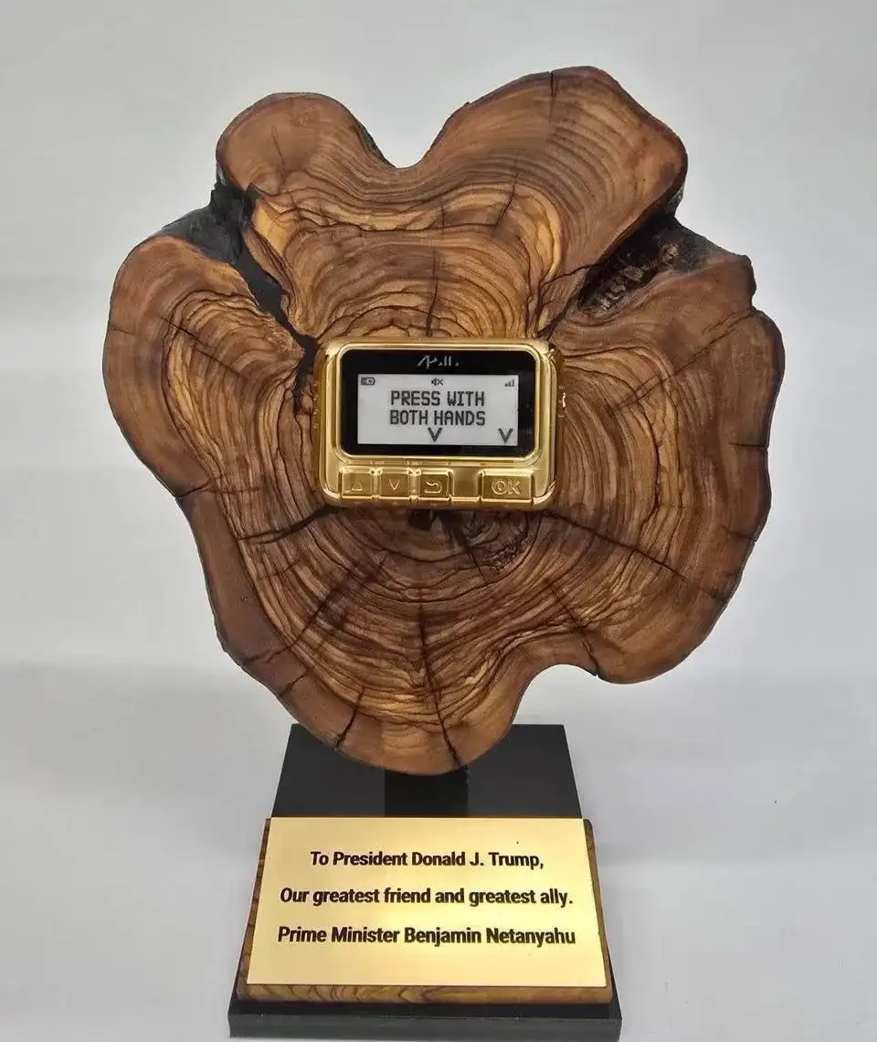 A golden, old-style video game controller is embedded in a large, ornate wooden base resembling a tree stump. The screen…