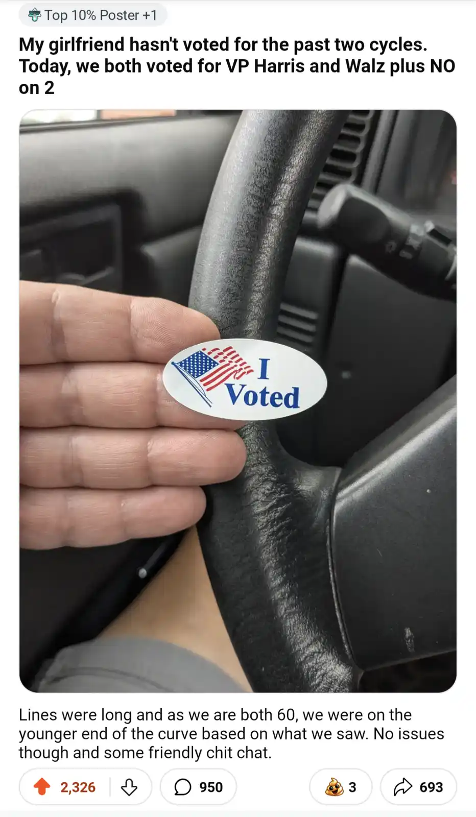 A hand holds an 'I Voted' sticker featuring a small American flag next to the text 'I Voted' against the backdrop of a car's…