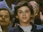 A sequence of six images shows a young boy in an audience, initially clapping, then slowly giving a thumbs-up gesture while…