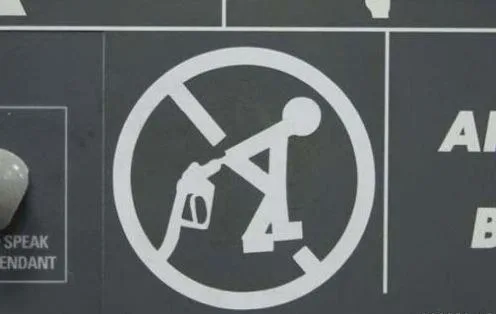 A close-up of a white circular 'no smoking' symbol on a dark gray panel, featuring a stick figure holding a lit cigarette…