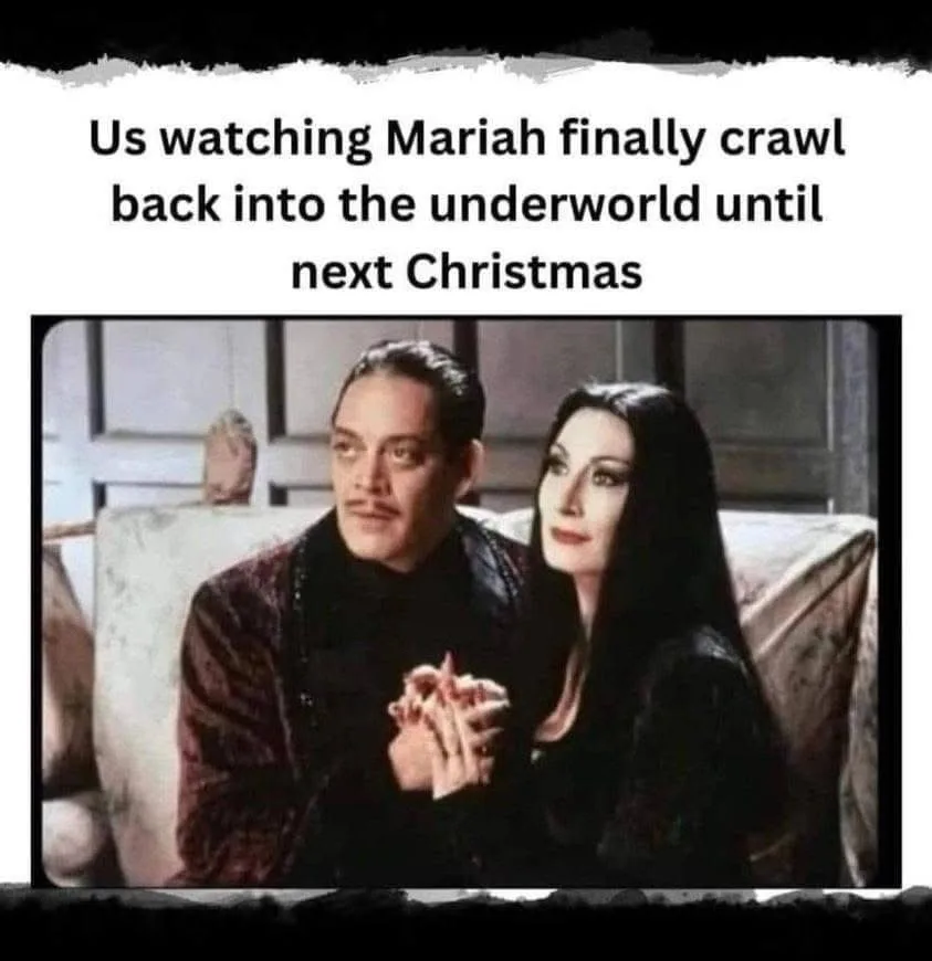 The image shows two characters, a man and a woman dressed in dark, gothic attire, sitting closely together on a couch. The…
