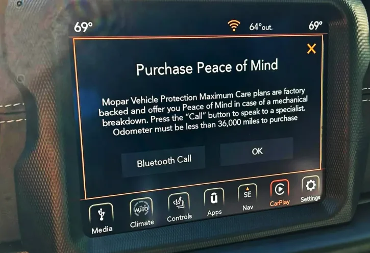 A car's infotainment screen displays a pop-up titled 'Purchase Peace of Mind,' advertising a Mopar vehicle protection plan…