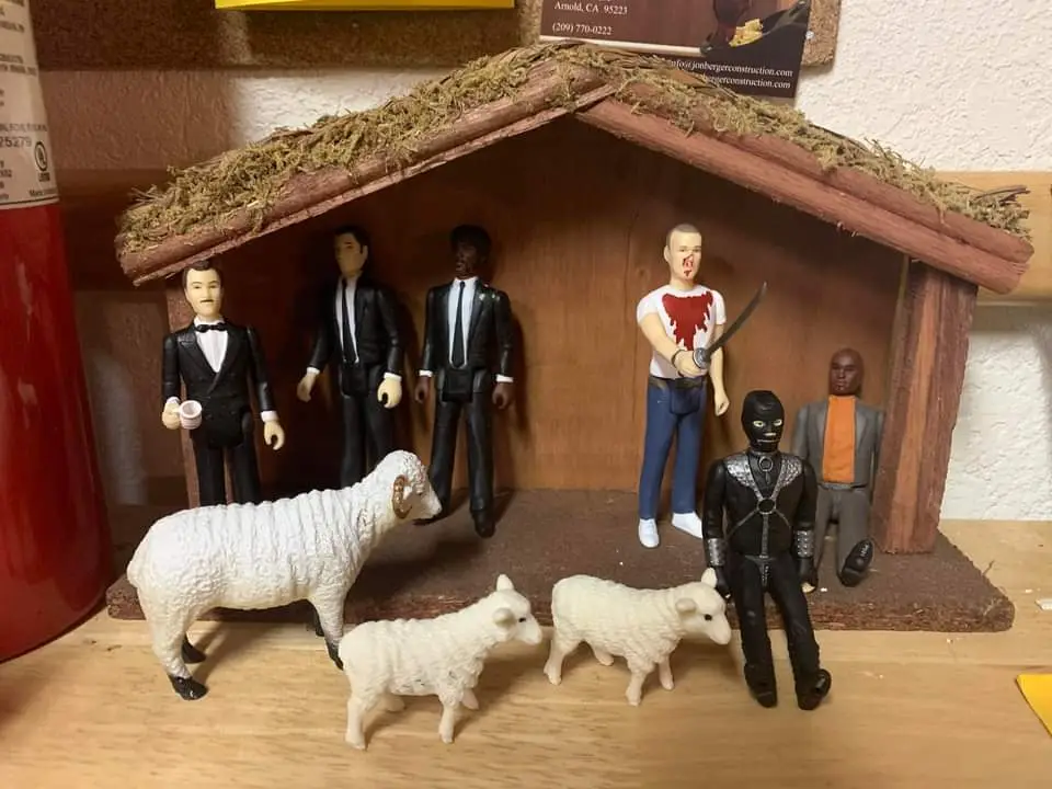 A nativity scene diorama is visibly altered with action figures instead of traditional figurines. Three men in black suits…