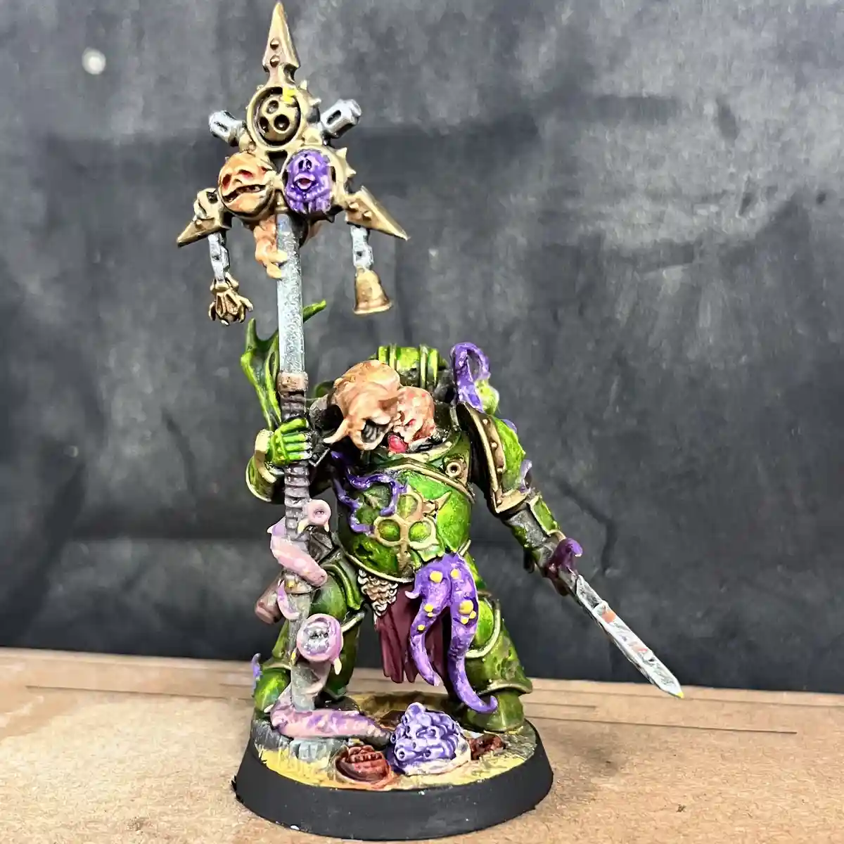 A heavily painted, grotesque fantasy miniature of a green-skinned, multi-limbed warrior with a large, ornate polearm topped…