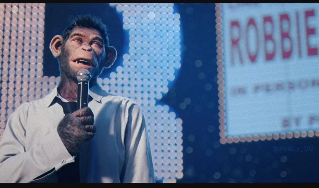 A chimpanzee dressed in a white shirt and black tie holds a microphone on a stage with a blue pixelated background. A sign…