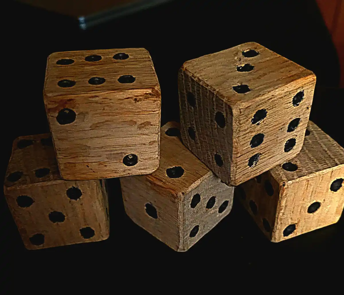 A pile of six rustic wooden dice with pitted holes for pips, arranged on a dark surface. The overlaid text reads 'six of…