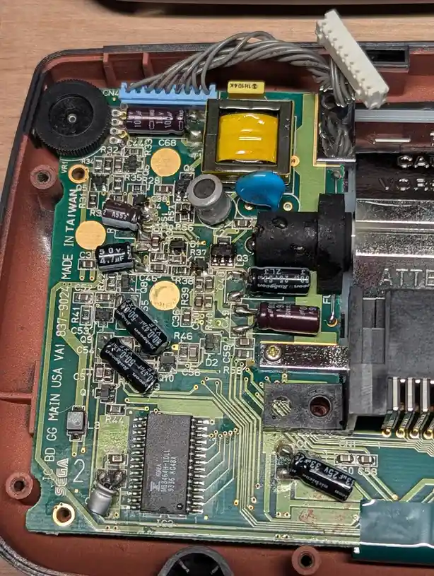 A close-up photo of the internal circuit board of a Sega Genesis console, showing various electronic components like…